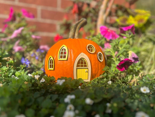 Pumpkin fairy house with a finished yellow fairy door and matching windows